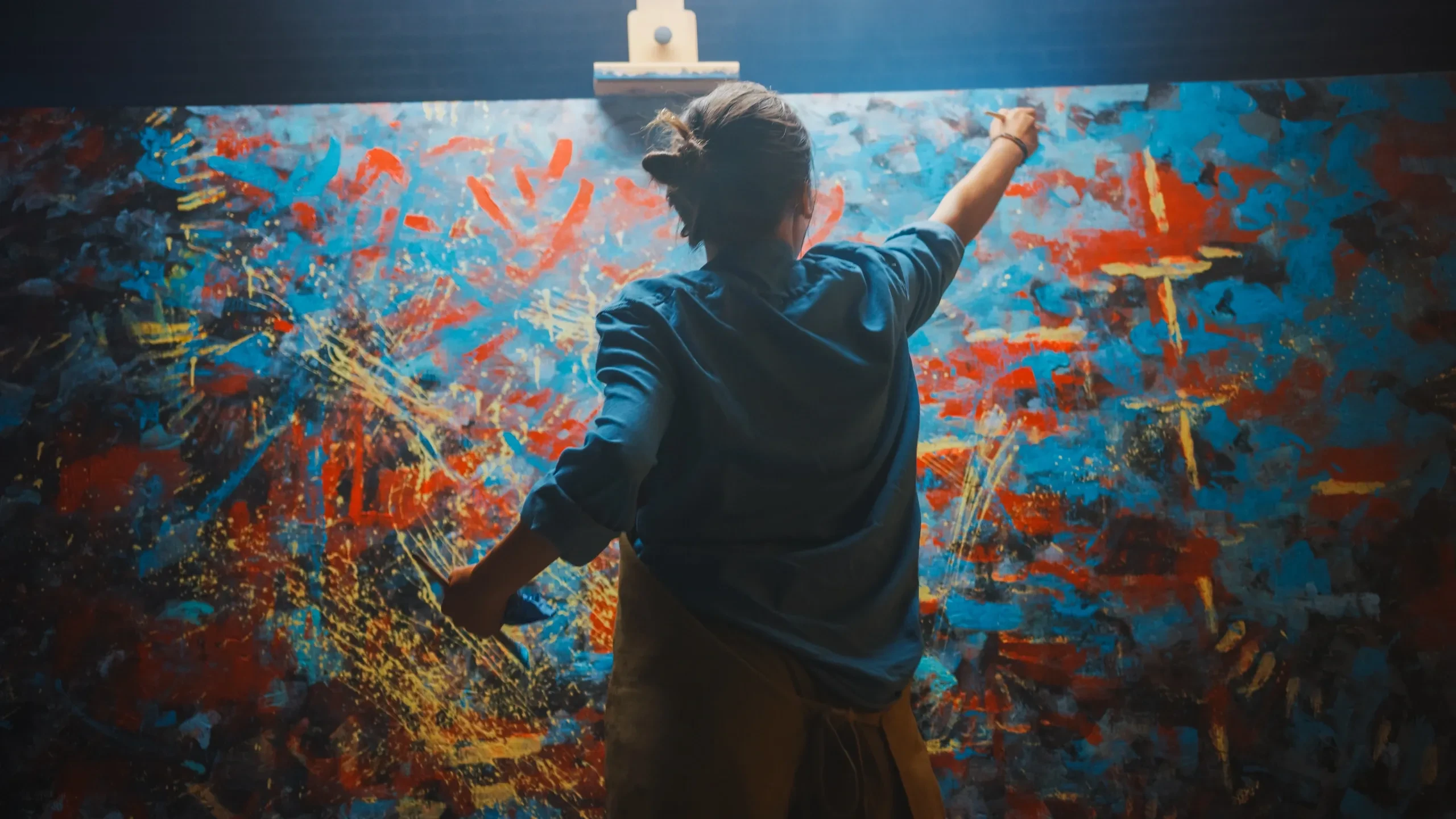 Youth participant painting a vibrant abstract mural